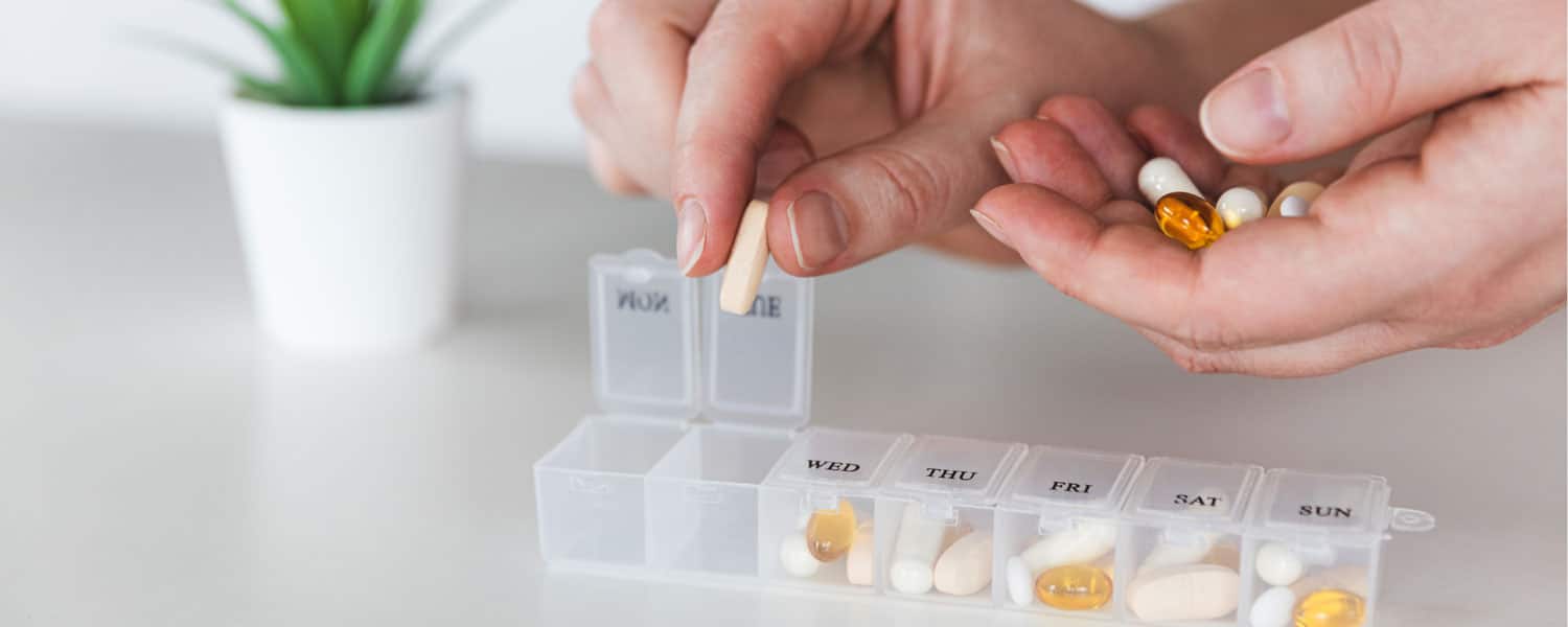 person putting pills in a pill box