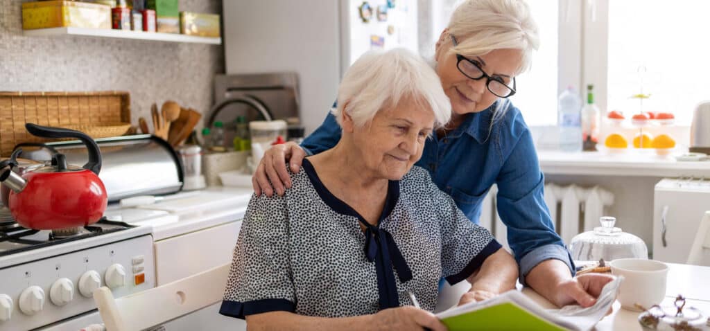 Woman helping an elderly relative at a table.