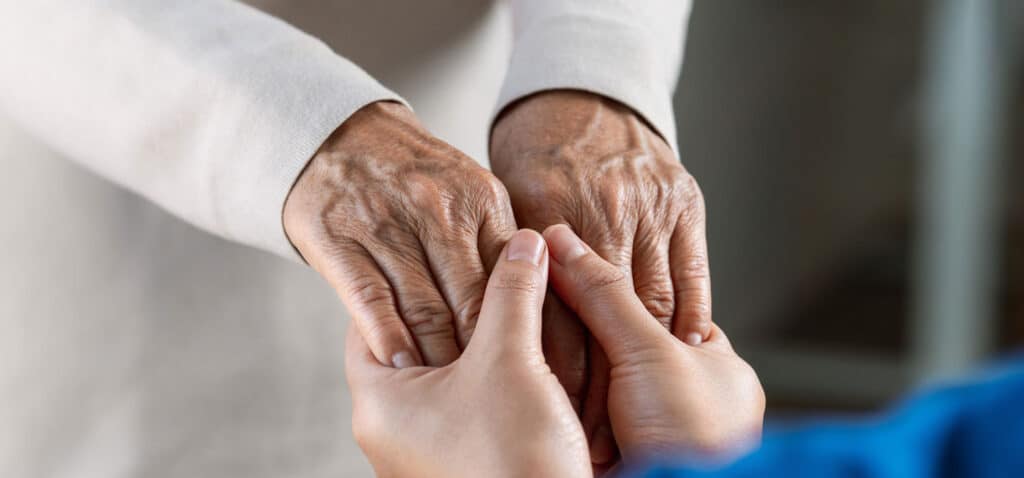 Caregiver holding the hands of a loved one with dementia