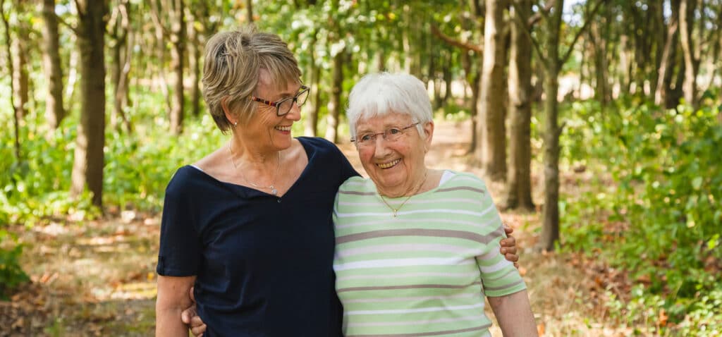 Two elderly woman walking in the woods