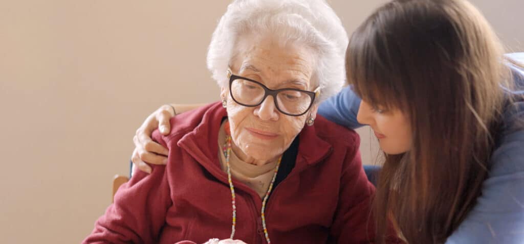 Caregiver with her arm around a loved one with dementia