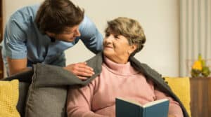 home health care provider putting a blanket on an elderly woman