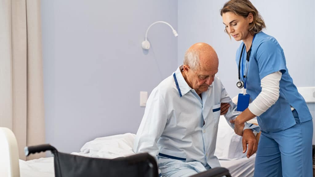 Nurse helping an elderly patient get out of bed